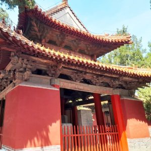 A small red temple with two traditional curved tile roofs.