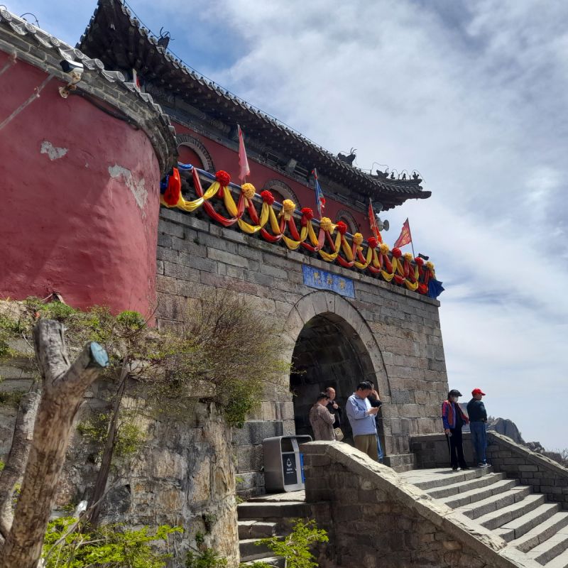Entrance to a temple with a stairway leading to an arched gateway and a curved tile roof.