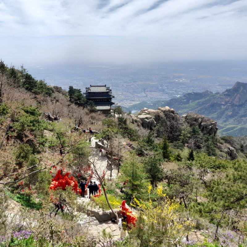 A view down part of the stairway path on Mount Taishan, with a temple and a big view of a city below.