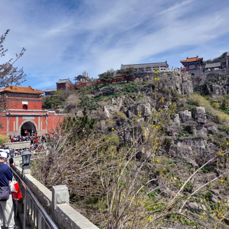 Crowds entering a temple on the left, more temples visible on the mountain behind that.