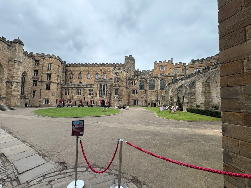 A classic castle courtyard: stone walls and crenellations along the tops of the walls.