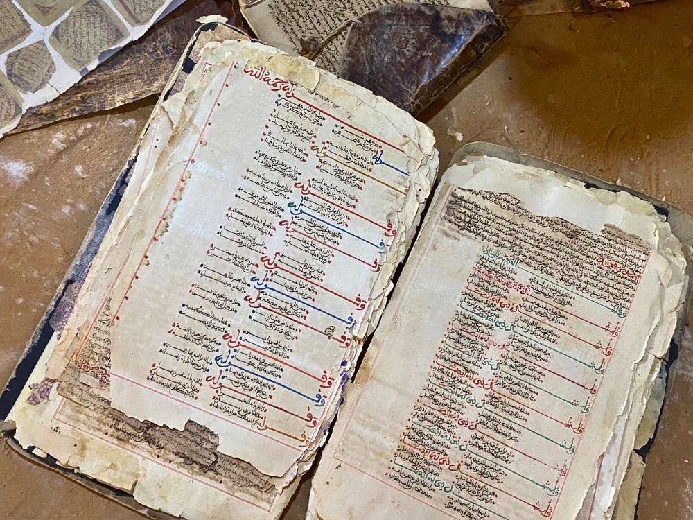 A very old book, open, with frayed edges and writing in Arabic script.