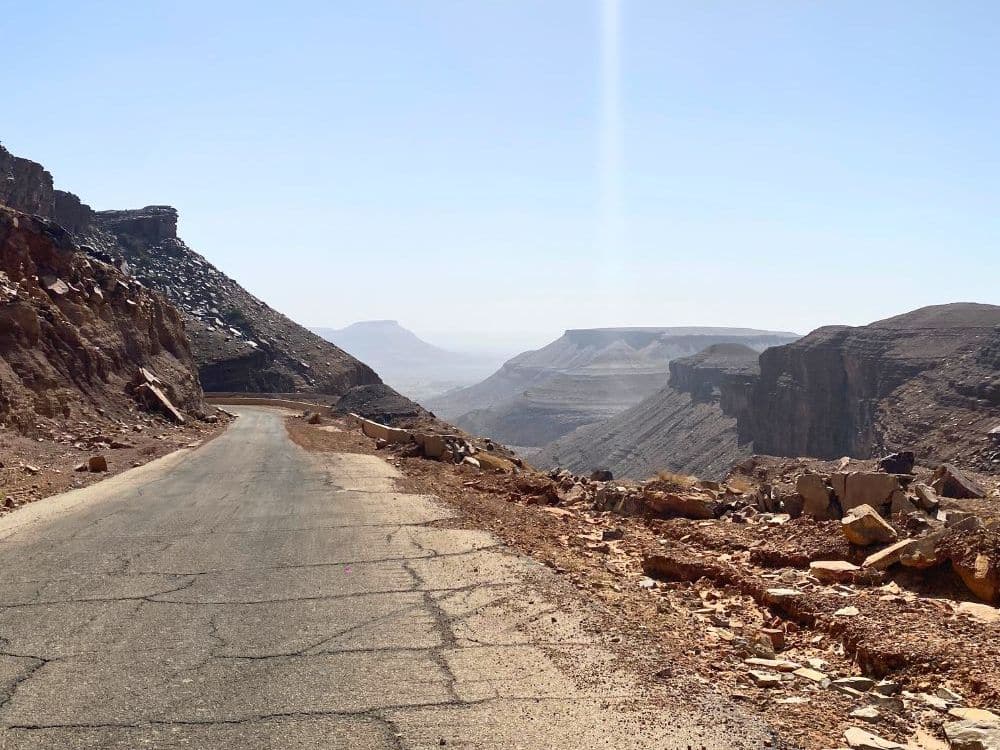 A paved road along the side of a mountain, damaged along the lower side.