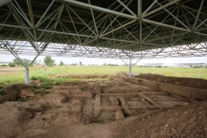 An archaeological site, showing the outlines of walls - the whole area is covered by a roof.