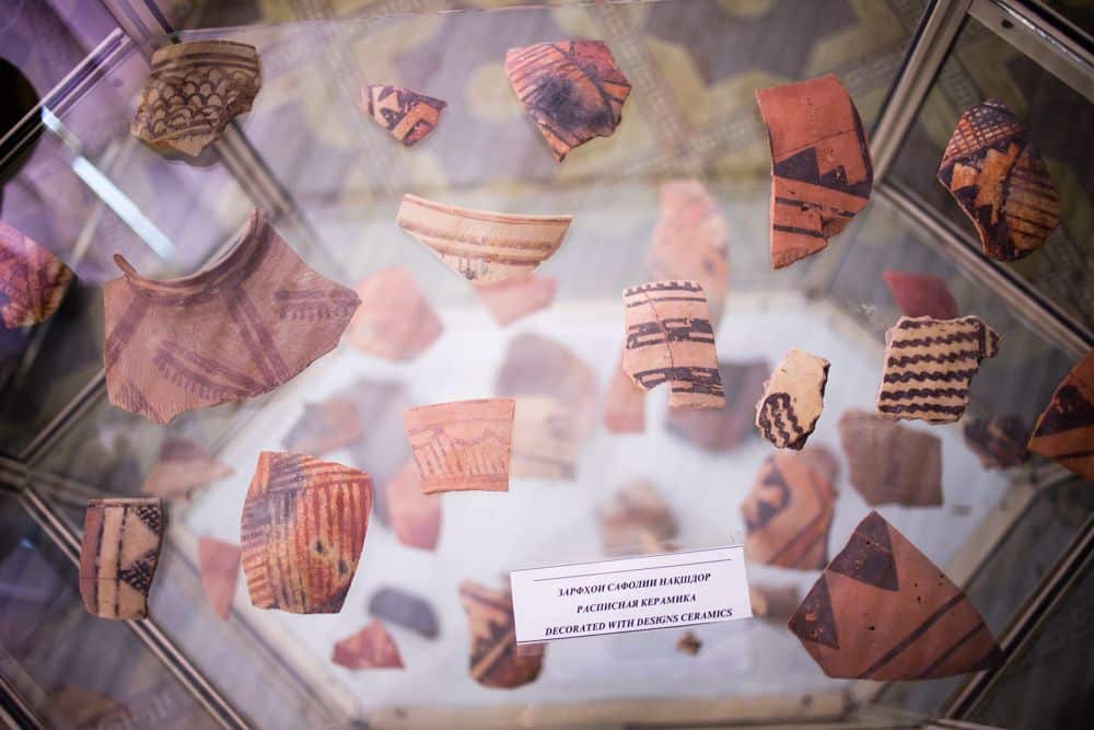 A display of small fragments of pottery with painted patterns. A small label says "Decorated with designs ceramics."
