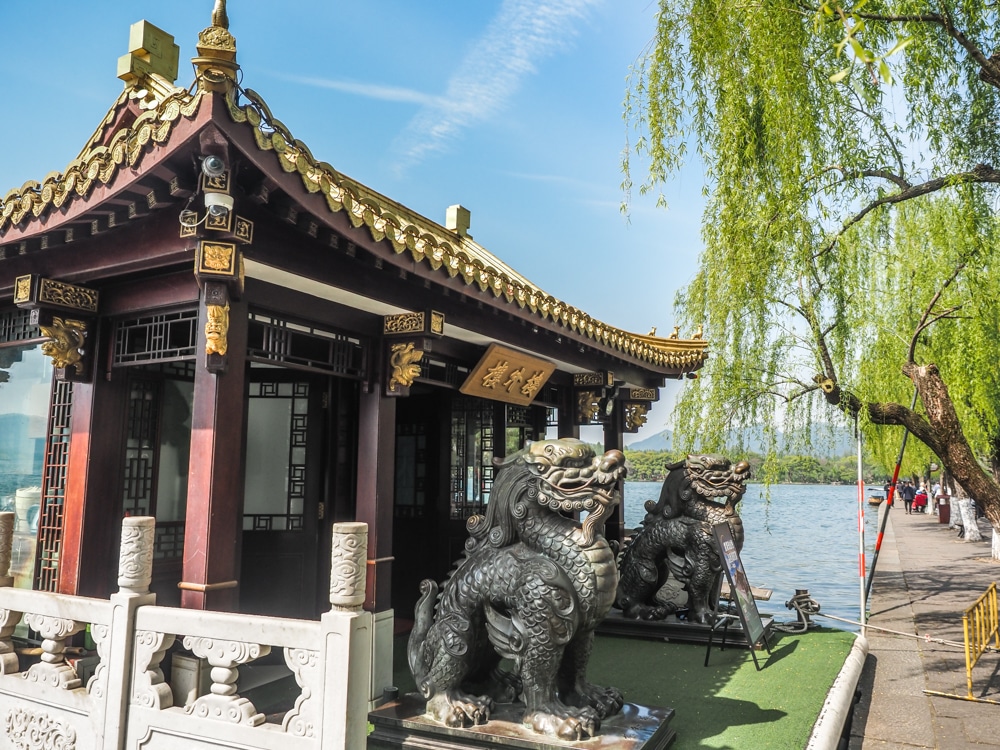 A small pavilion beside the lake, with large stone lions guarding the entrance.