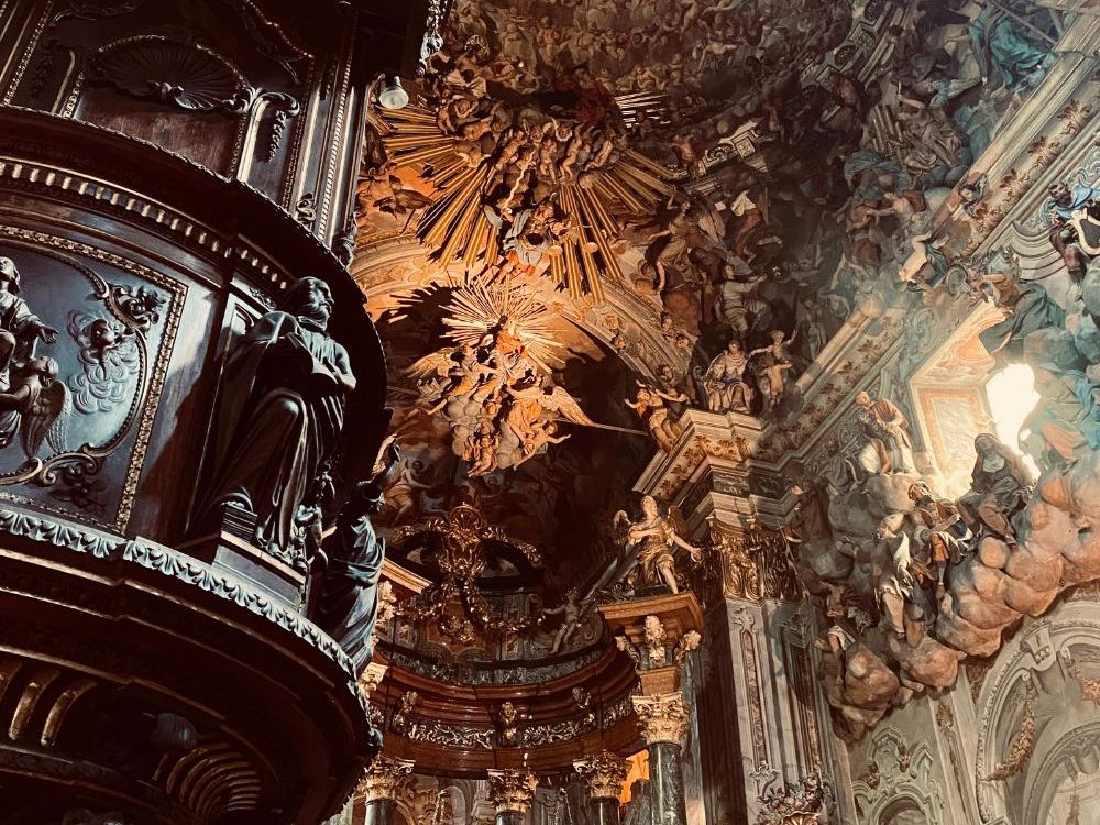 Incredibly ornate archway and ceiling: very baroque with sculpture and painting.