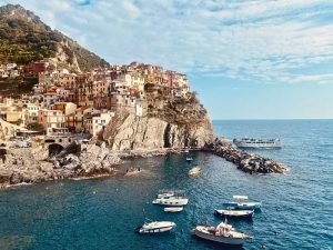 Houses on cliffs above a bay with moored boats.