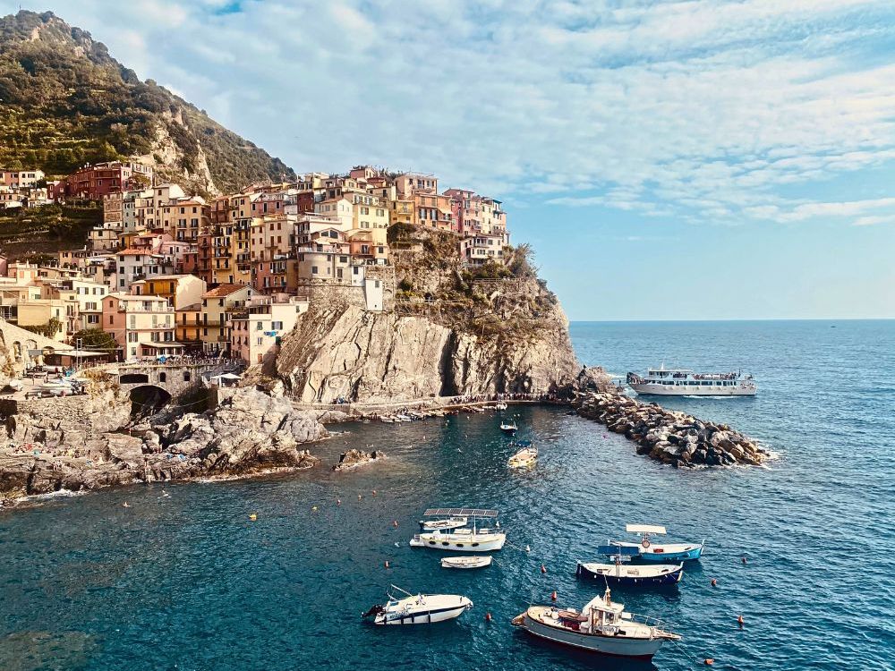Houses on cliffs above a bay with moored boats.