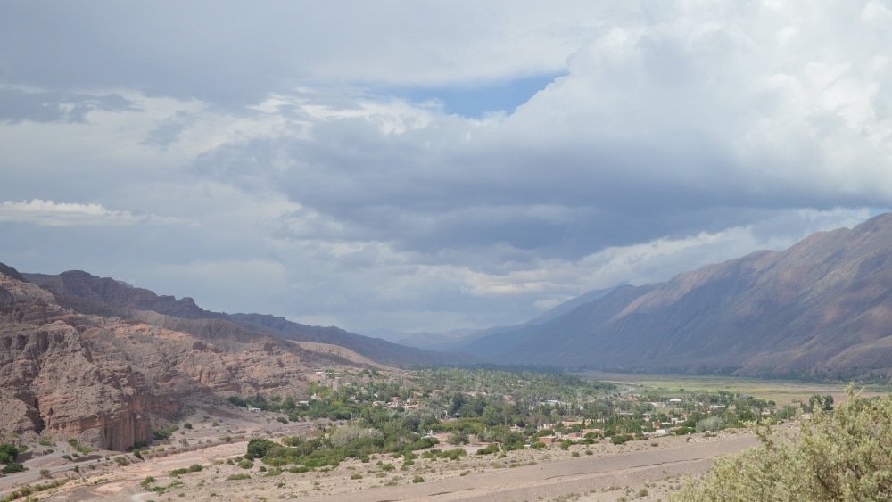A view down into a valley with a two-lane road and a small village; mountains along the edge of the valley.