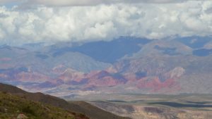 A view across a valley to lines of colorful mountains on the other side.