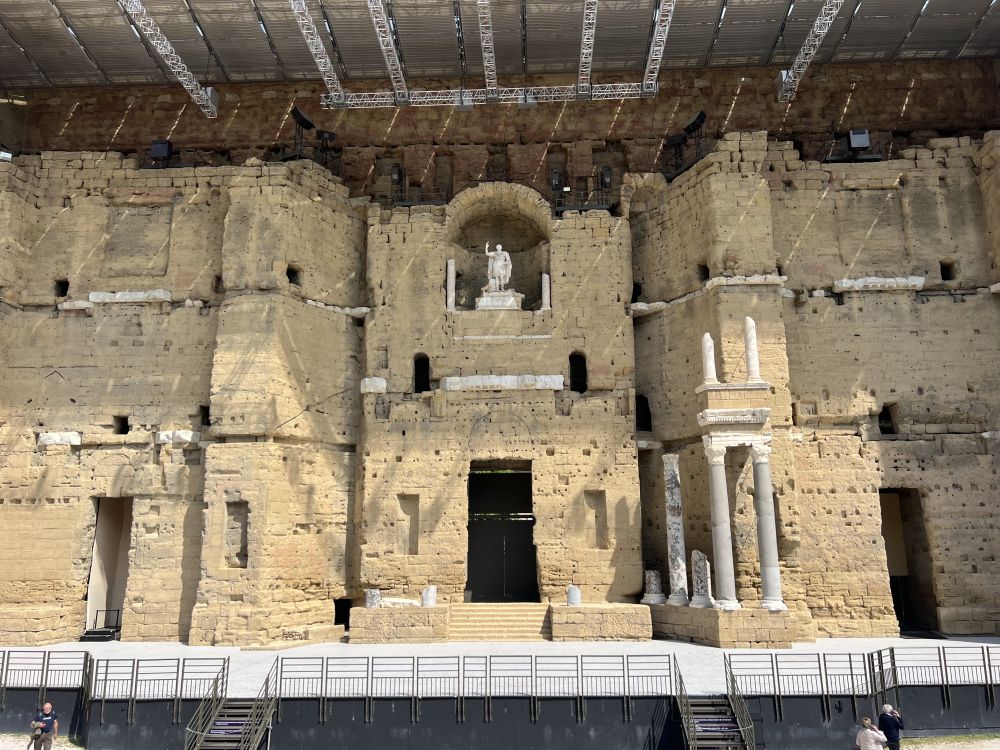 A closer view shows the theater backdrop with a statue at its center, and pillared elements on either side.
