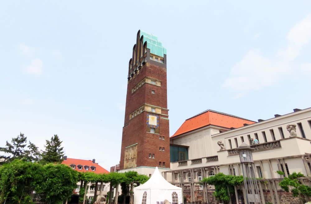 A tall brick tower with a top of 5 arches, with the middle being the tallest.