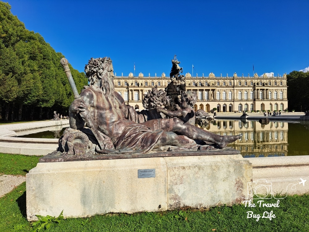 An ornate statue with a huge palace in the background, one of the Palaces of King Ludwig II of Bavaria.