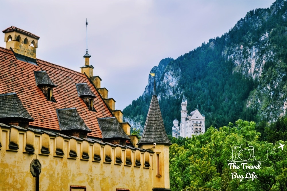 nearby, part of a castle wall and roof. Beyond, a fanciful castle in the distance.