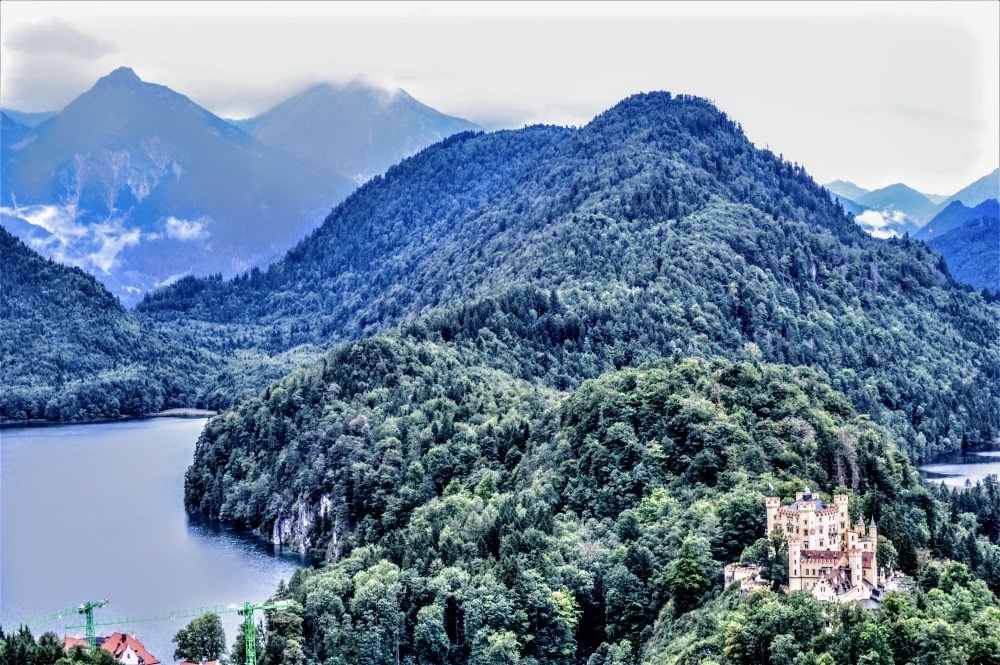 View of forested hills ,mountains and lakes between them, with a castle that is not one of the Palaces of King Ludwig II of Bavaria.