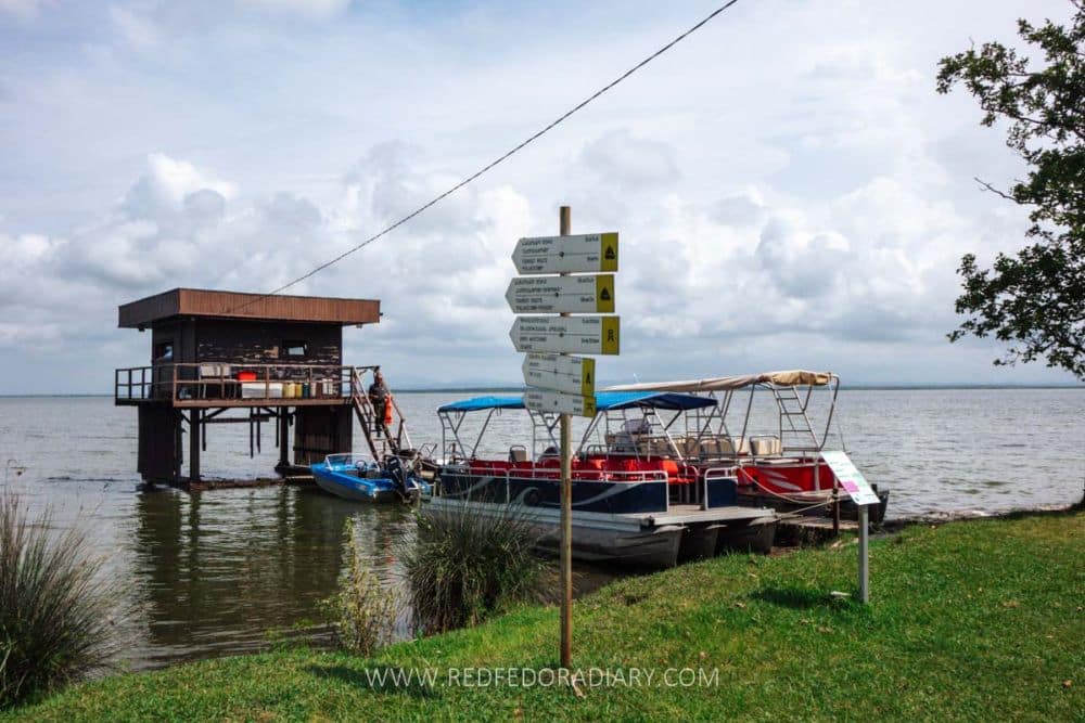 A boat moored on a lake and a small building on stilts over the water.