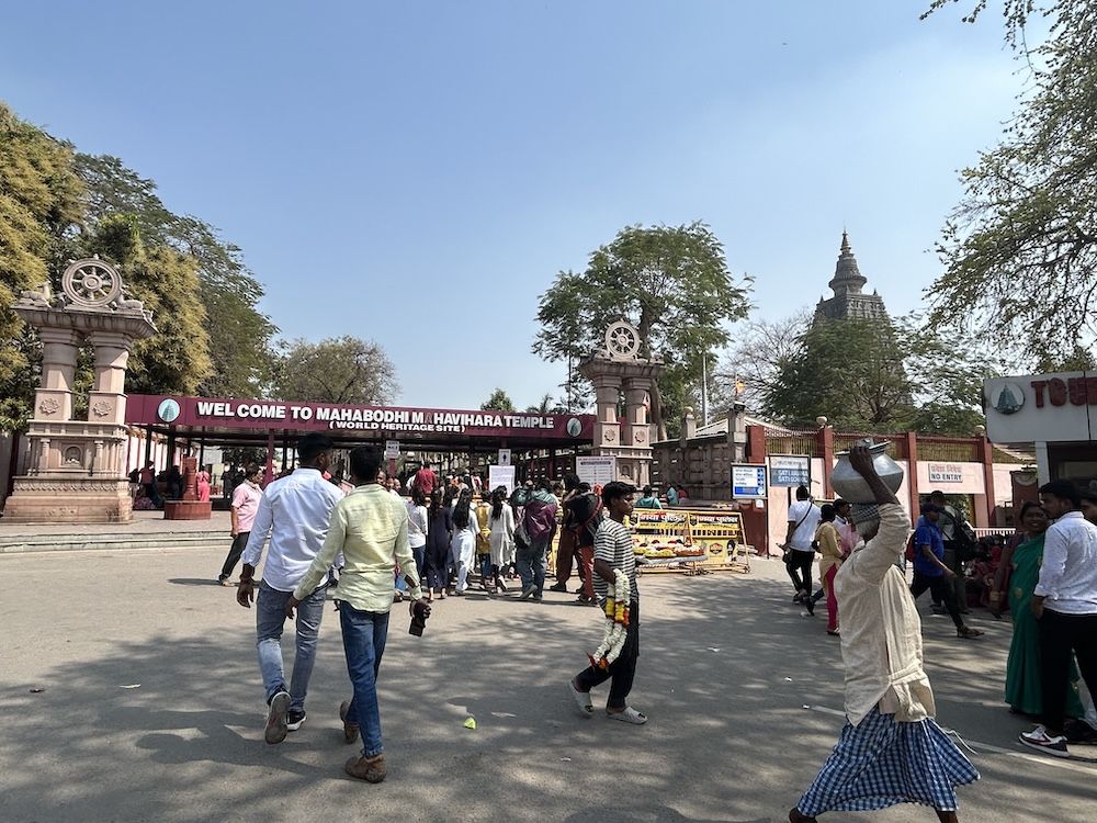 The entrance gate to the complex with many people walking in various directions.