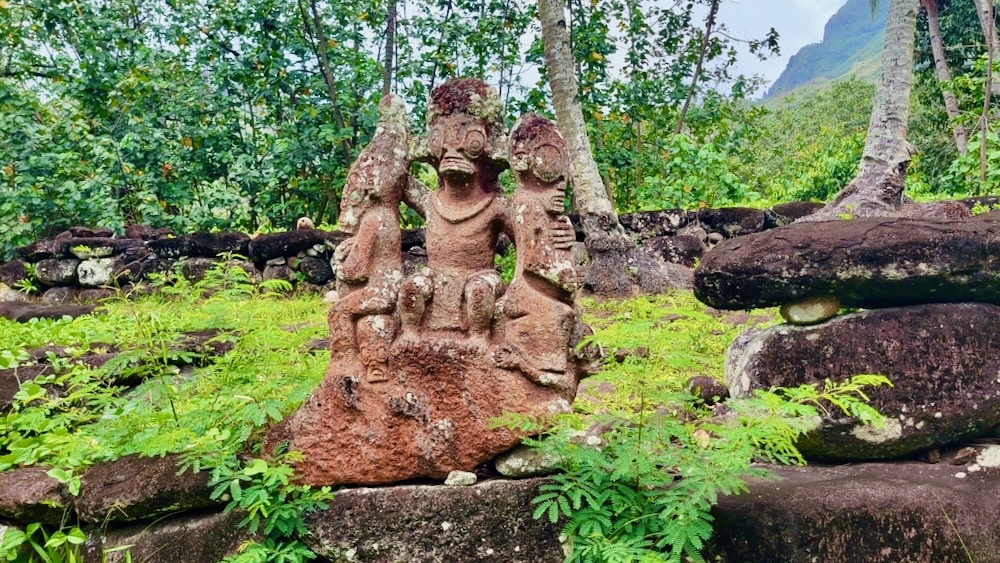 A stone statue of a person? or monkey? with its arms around two other figures.