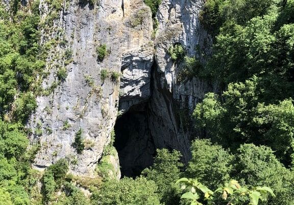 A cave entrance in a flat rock cliff wall.