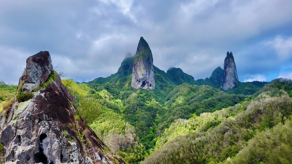 a green tropical landscape, very mountainous, with several pointy granite towers sticking out above the greenery.