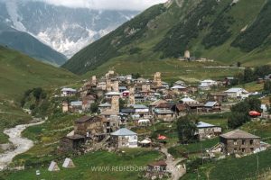 A village with stone towers here and there, in a valley with mountains around it.