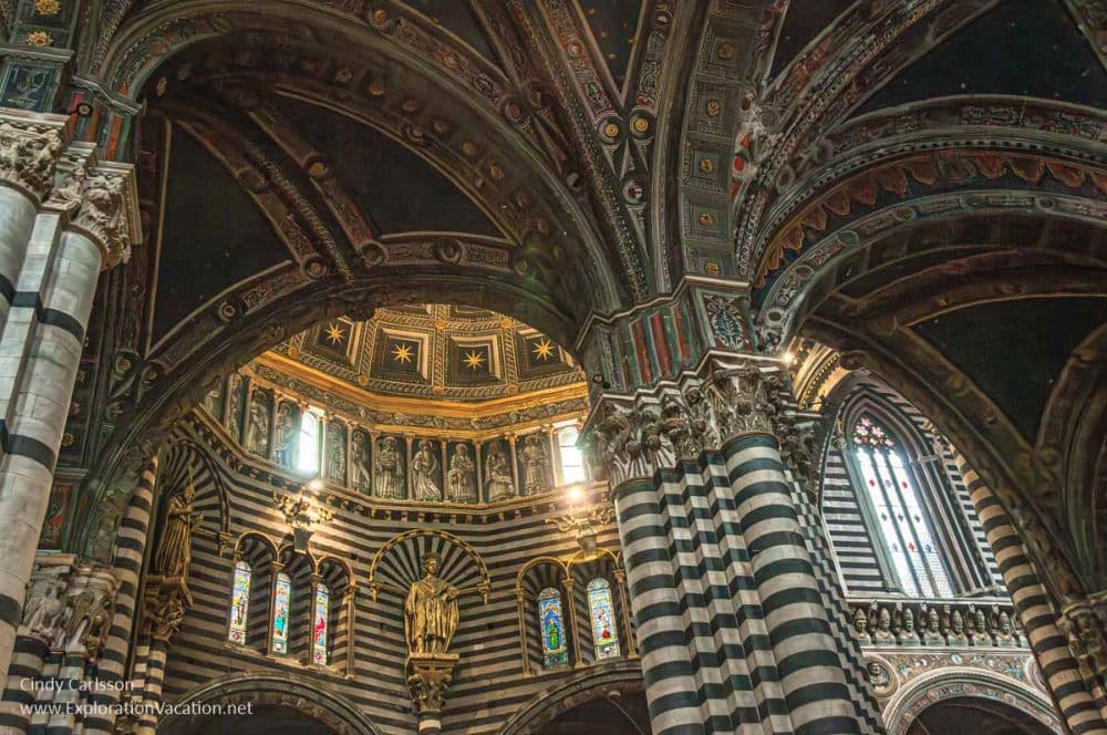 Cathedral interior looking upwards, with detailed arches and ornate repetitive carved patterns or stripes of different colors of stone covering every inch.