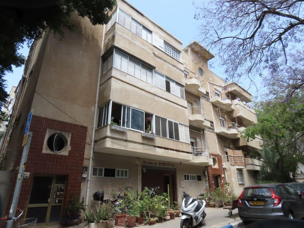 A white building with horizontal balconies and windows extending out from the facade.