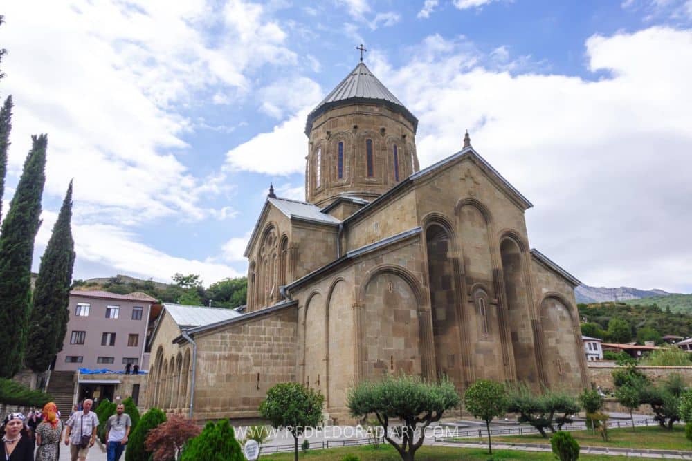 A stone building with Romanesque arches (without windows in them) and a round tower in its center.