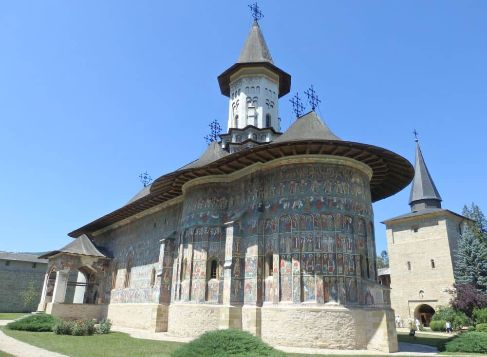 A small rectangular church with a rounded apse, eaves that extend from the roof, and a small round bell tower.