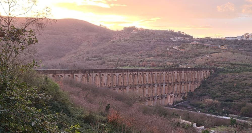 The aqueduct spans a valley with 3 layers of arches on top of each other.