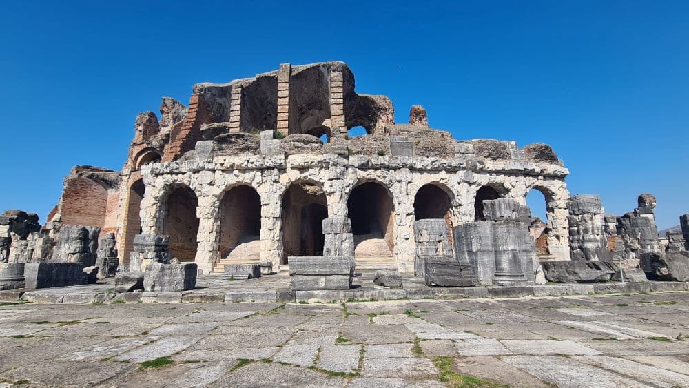 A view of the amphitheatre with an arched portico on the ground floor and a few columns on top of that.
