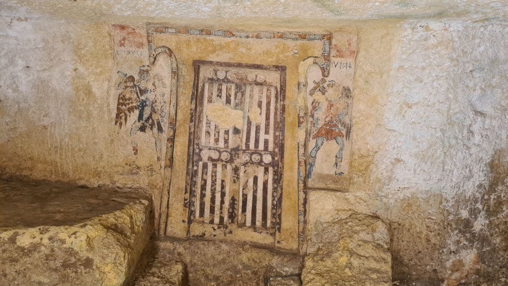 A door painted onto a wall, with stripes, perhaps to make it look like a wooden door, and a figure on either side of it.