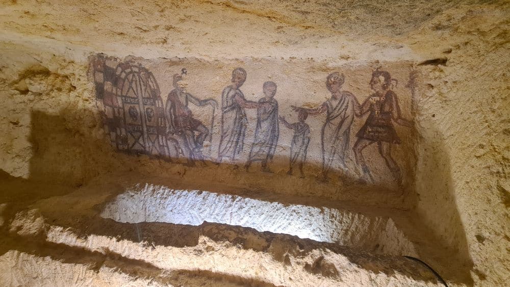 A small and rather blurry scene of people above a carved pit.