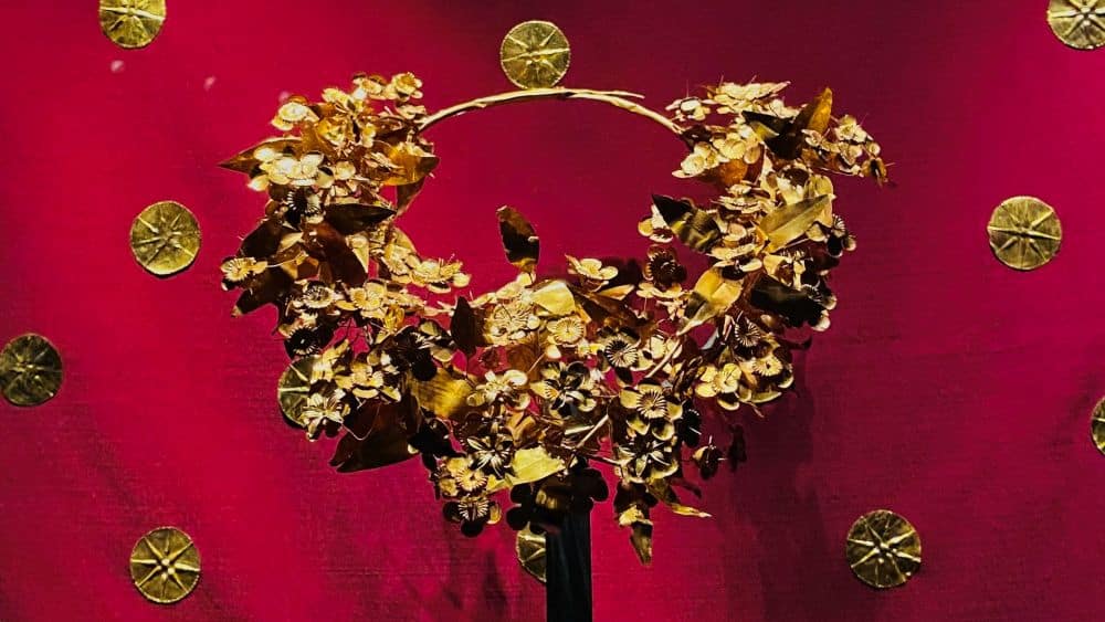 A wreath with gold leaves and gold flowers around about 3/4 of the circle.