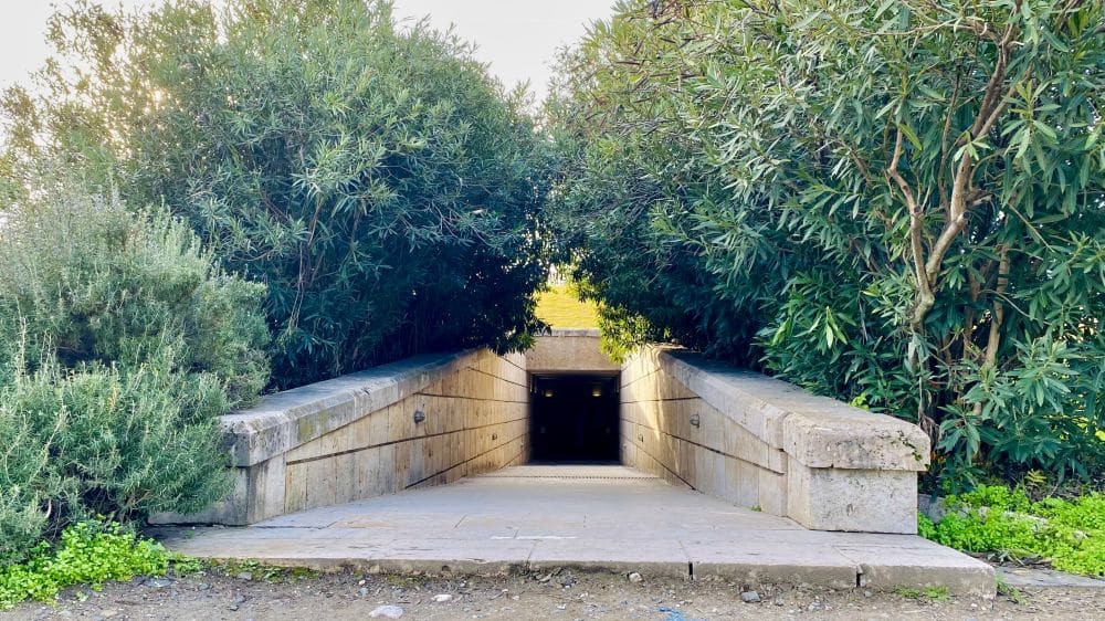 A ramp heading down to an underground entrance. Trees on either side.