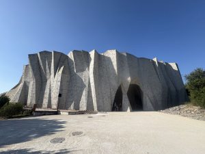 A modern building that looks like a white rock outcropping or an iceberg and houses the Grotte Chauvet replica.