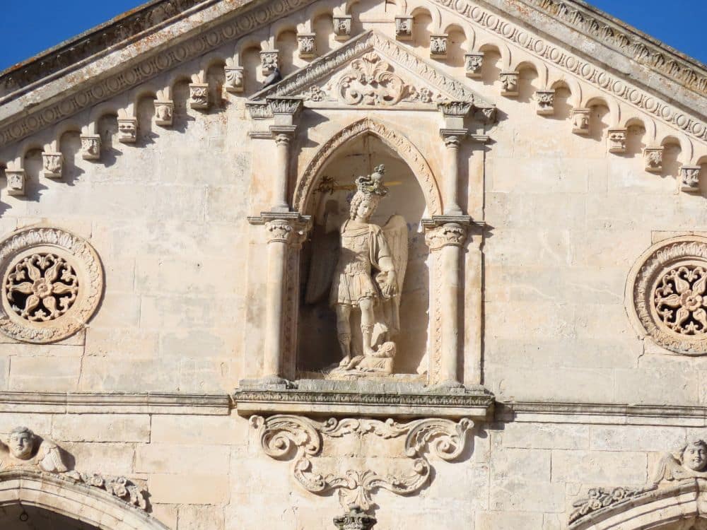 A niche framed by classical-style carved pillars shows a statue, presumably of St Michae.