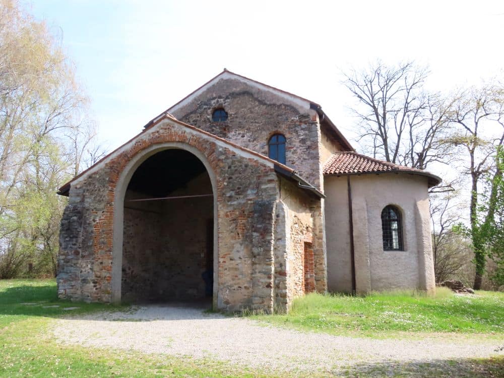 A small church with a roofed entrance and a rounded side apse visible.