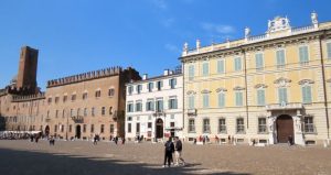 Three buildings, each a few stories high, and each a different color: red-brick, white, and yellowish.