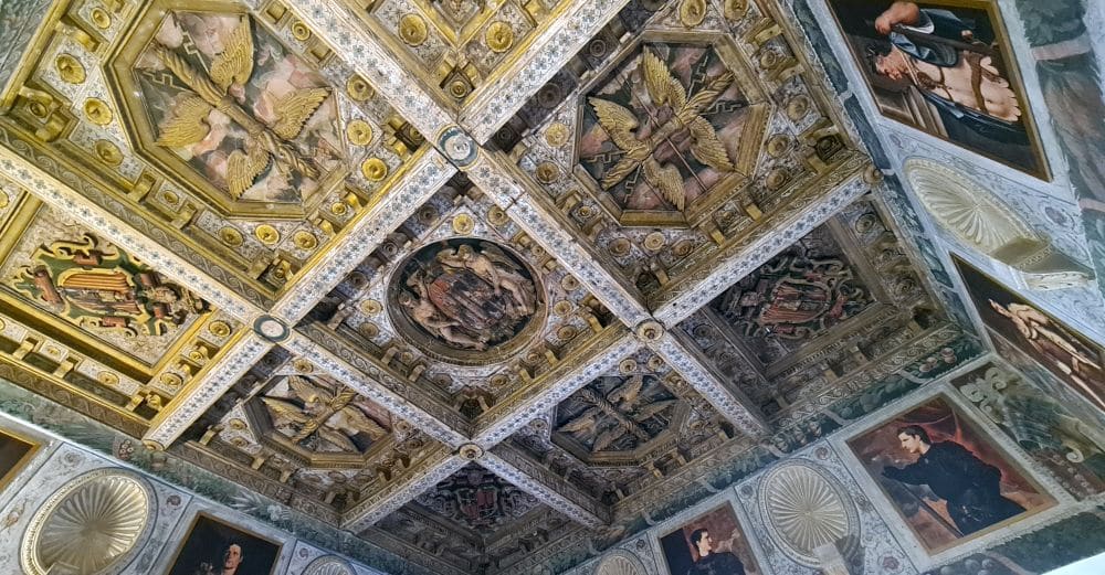 Ornate ceiling divided in panels, carvings within each square, with the carvings painted brightly.