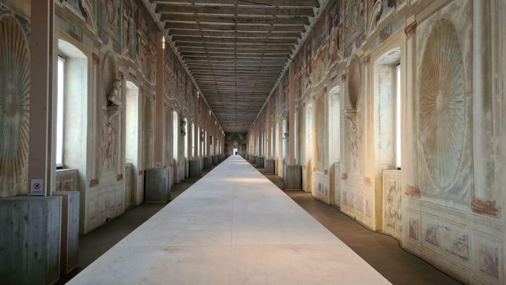 A very long, narrow hallway, with a narrow white table down the middle. Windows on both sides.