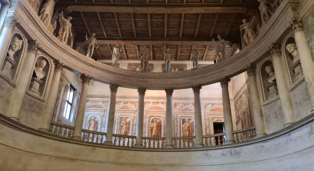 A colonade of pillars with a row of classical-style statues along its top.