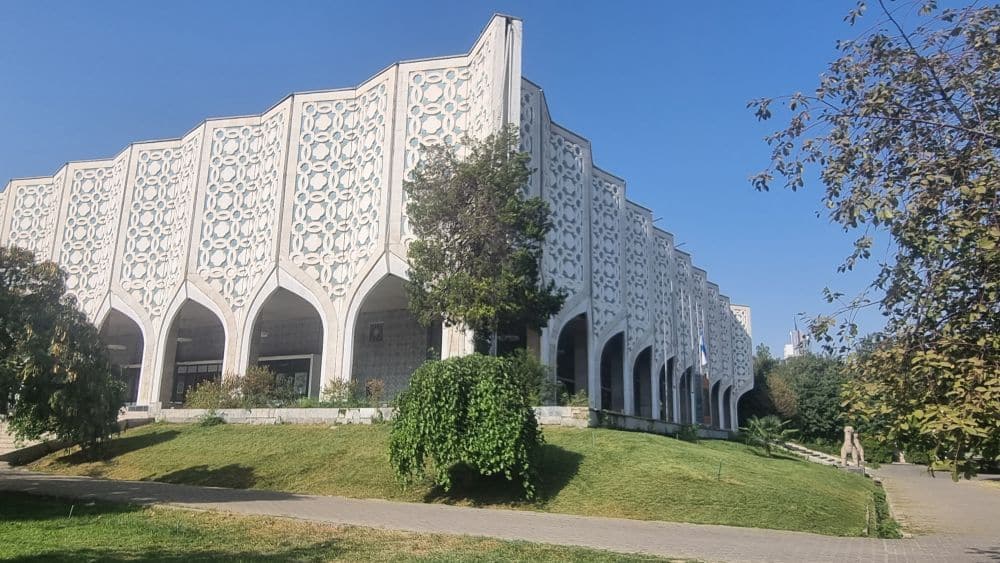 From this view, 2 sides of the building are shown: arched portico around the bottom floor, patterns repeating above that one slightly fluted panels.