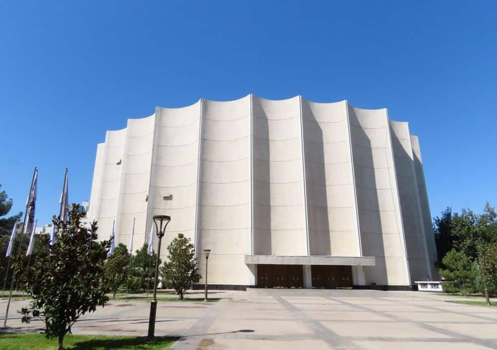 A white, rounded facade with no windows, but with vertical fluting like a doric column.