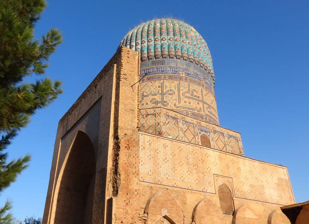 A brick building with a flat facade seen from the side, which allows a view of the brilliantly tiled and fluted dome.