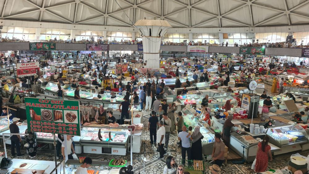 Looking over a vast space filled with food vendors and shoppers. Above, a very high up roof.
