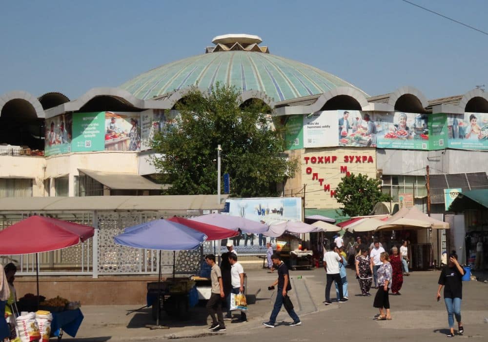 Behind a jumble of shops and billboard, a large blue dome is partly visible.