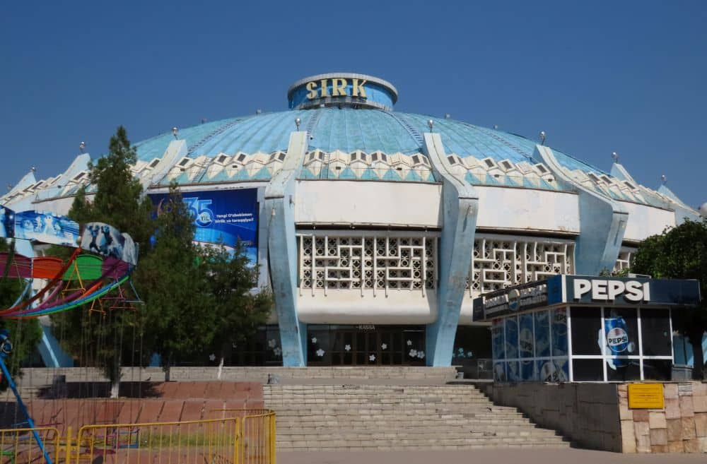 A flat, round building topped by a blue dome with ribs up the sides.