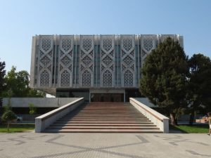 A long gradual staircase leads to a rectangular block of a building with a repeating vertical pattern in the concrete.